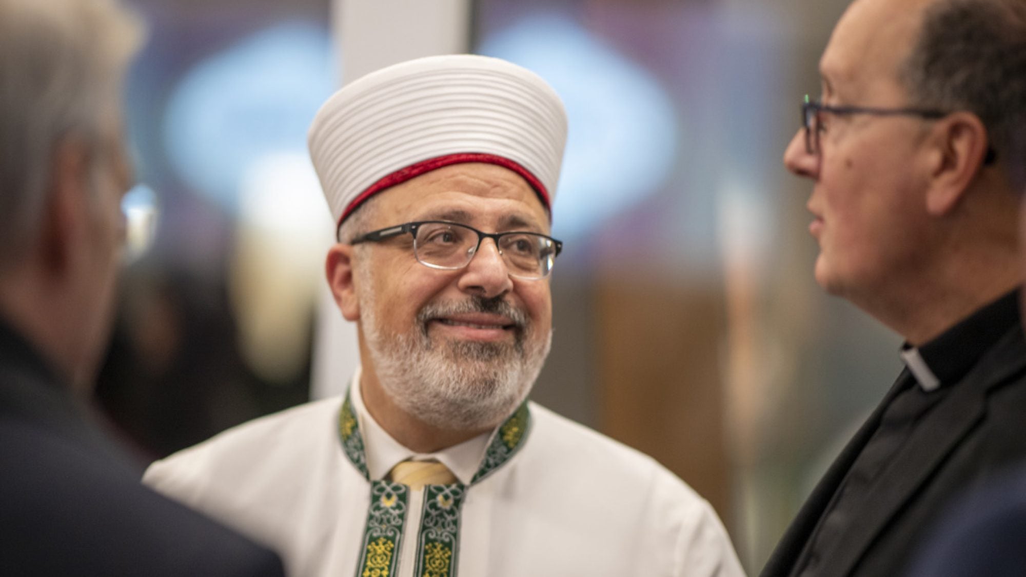 Imam Yahya Hendi smiles in a white robe and a traditional hat.