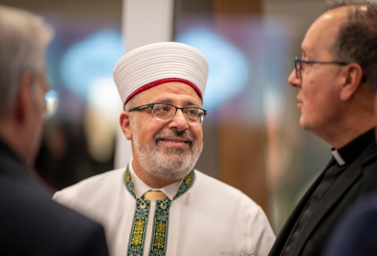 Imam Yahya Hendi smiles in a white robe and a traditional hat.