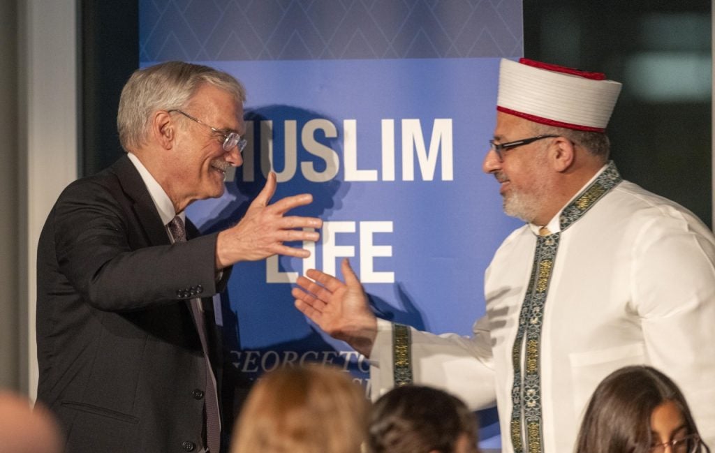 Georgetown Interim President Robert Groves reaches to hug Imam Yahya Hendi, Georgetown's Muslim chaplain, at a celebratory event. 