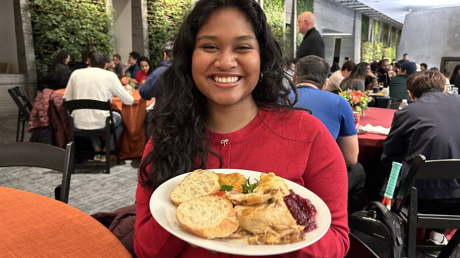 A young woman in a red sweater with a plate of food