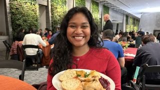 A young woman in a red sweater with a plate of food