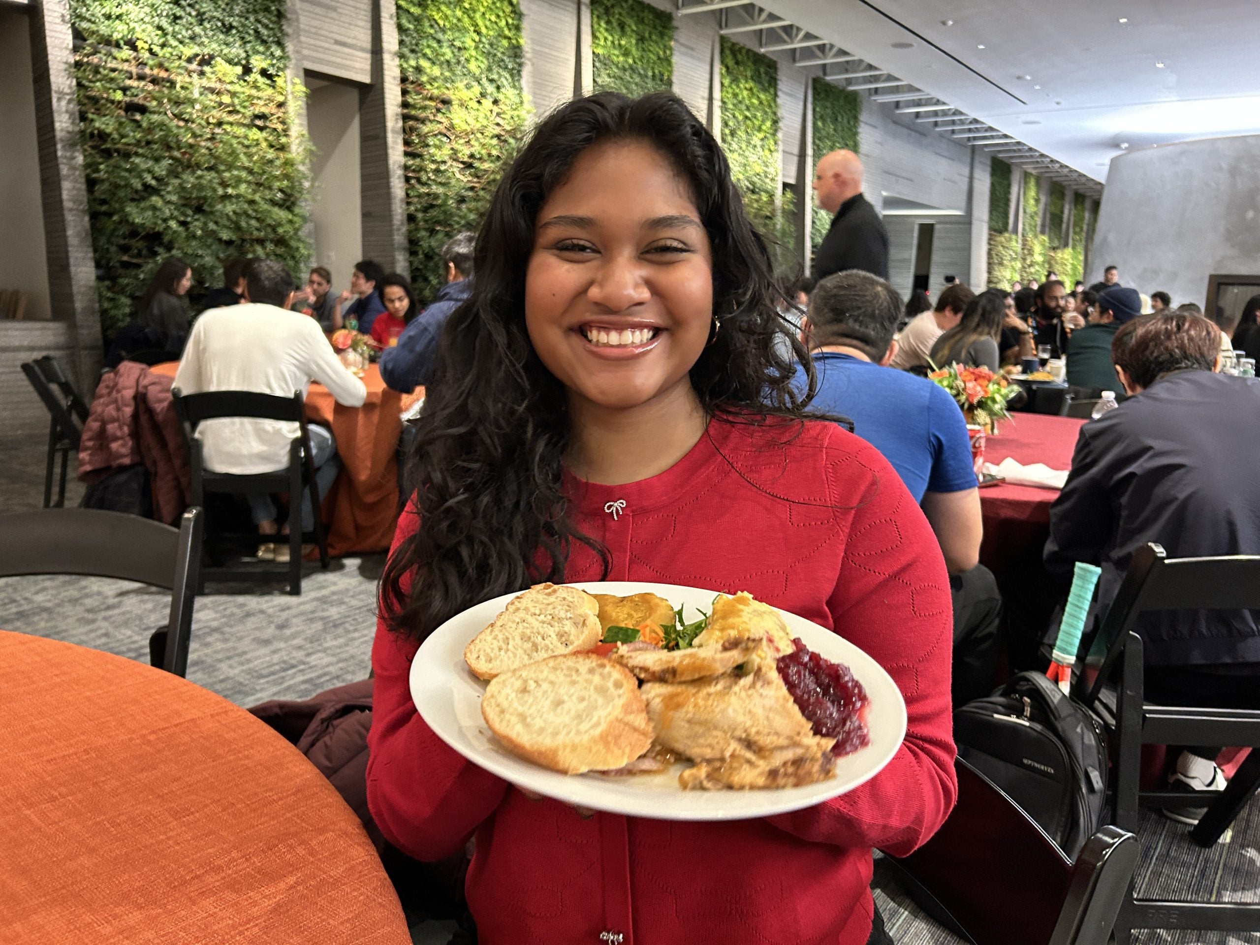 A young woman in a red sweater with a plate of food