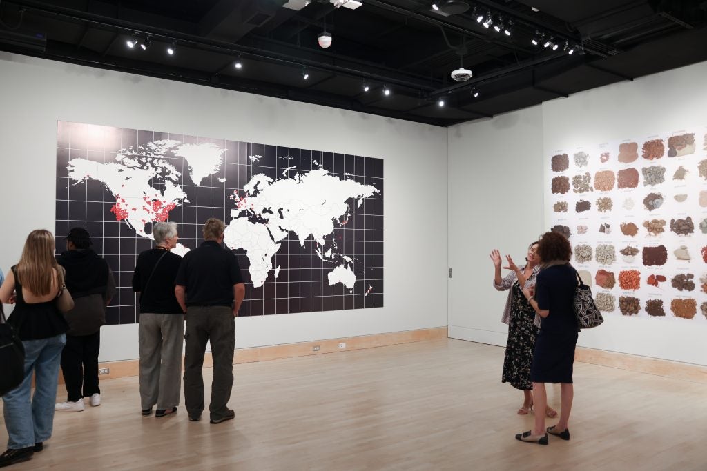 A group of people visit an art gallery and look up at a map of the world.