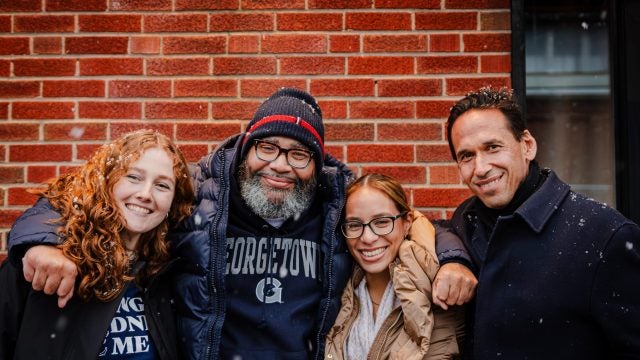 Two female student pose with a recent exoneree and their professor.