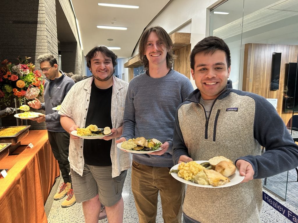 3 young men with plates of Thanksgiving food