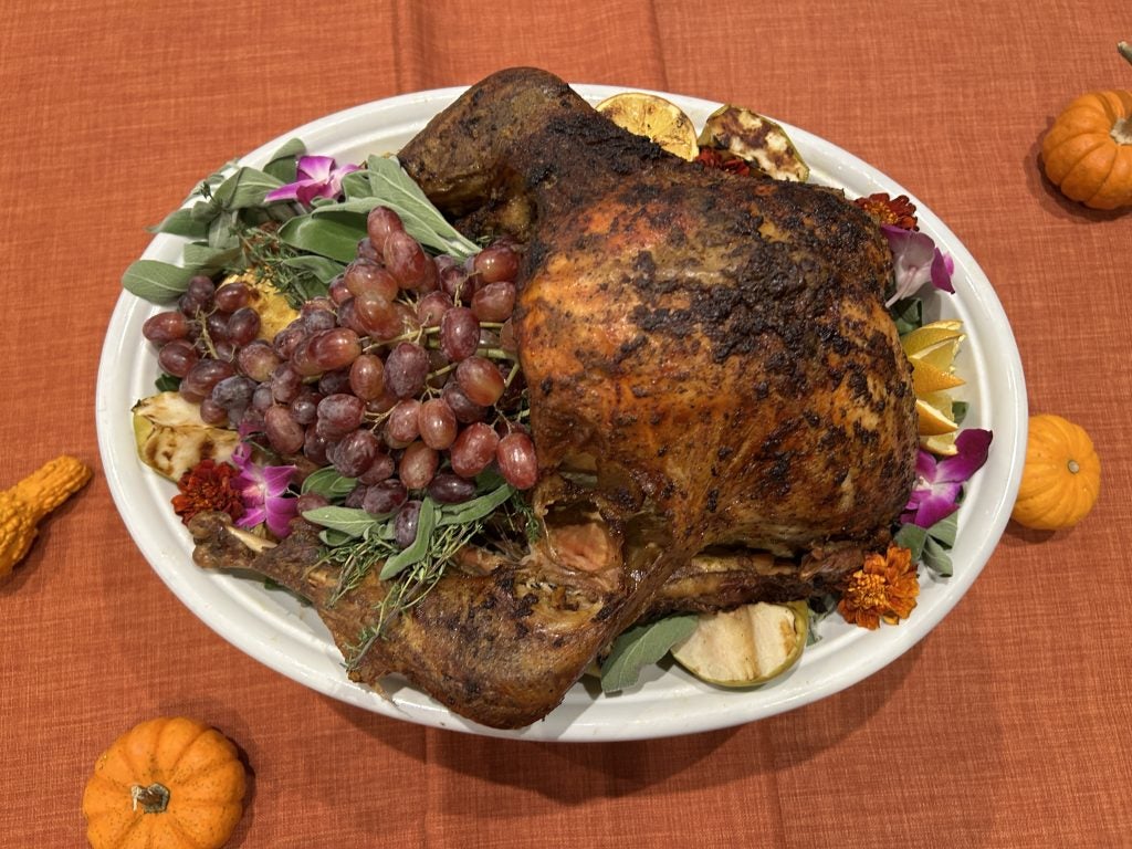 A whole turkey roasted on a plate with grapes