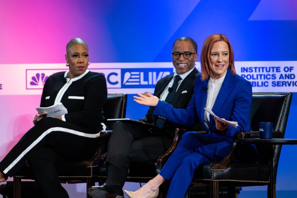 Woman in blue suit speaks with two other people on stage