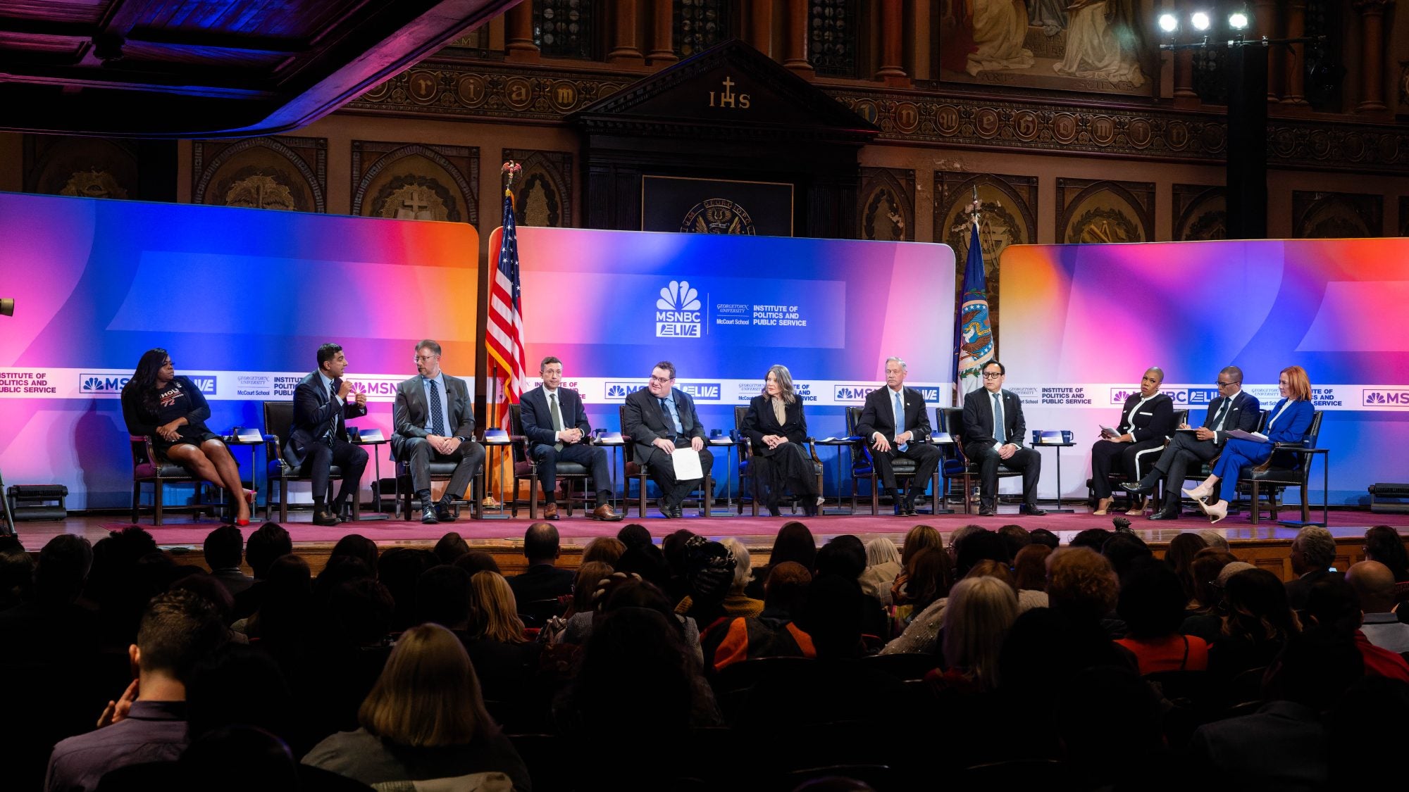 A group of people on stage speak at a candidate forum in Gaston Hall