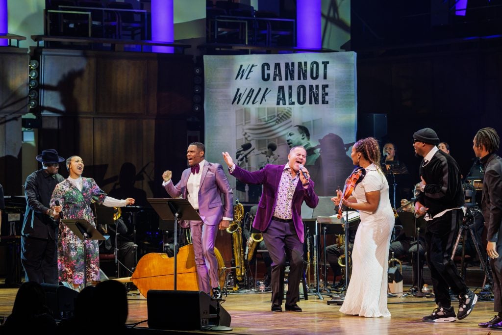 A group of performers sing and dance on a stage.