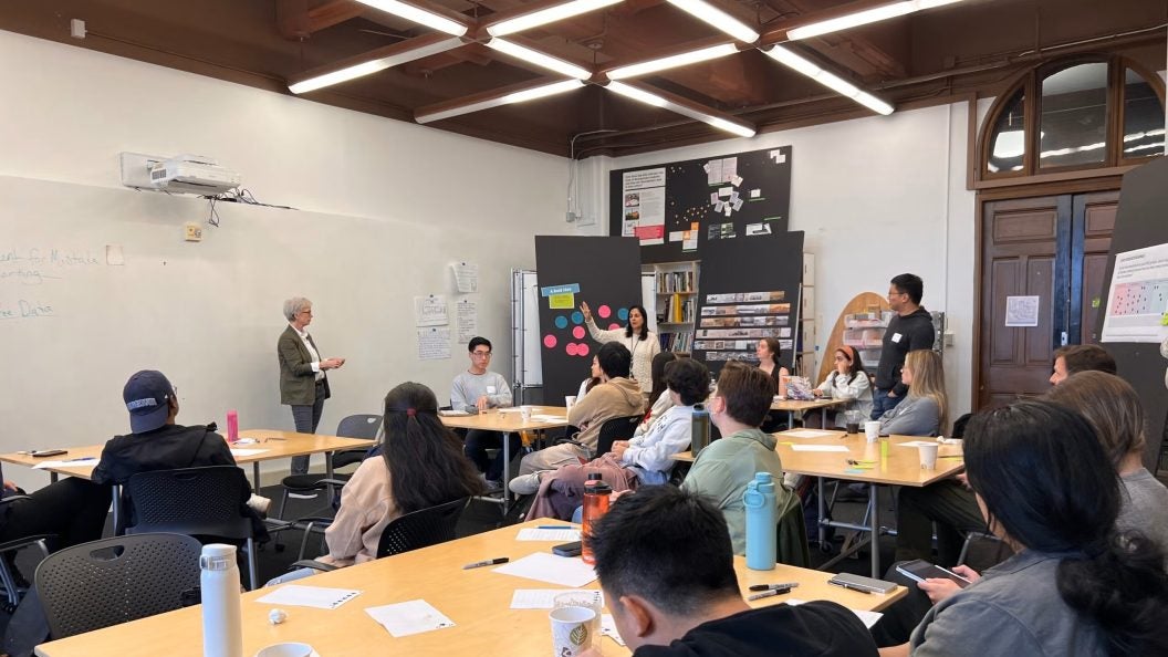 Two professors speak to students in a classroom