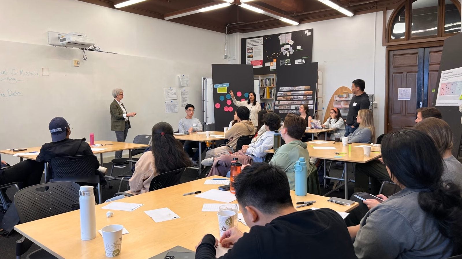 Two professors speak to students in a classroom