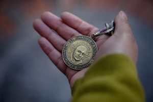 A gold medallion with the face of St. Ignatius in a Black man's hand