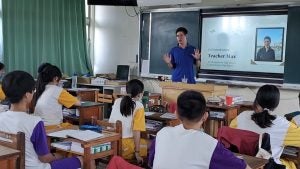 Goetz in a blue shirt teaching to a group of students in the classroom.