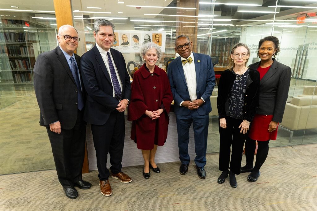 A group of people pose together in front of an exhibit in a library.