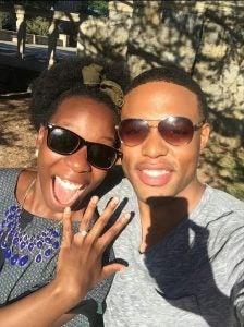 A woman holds up her engagement ring next to her fiancee. 