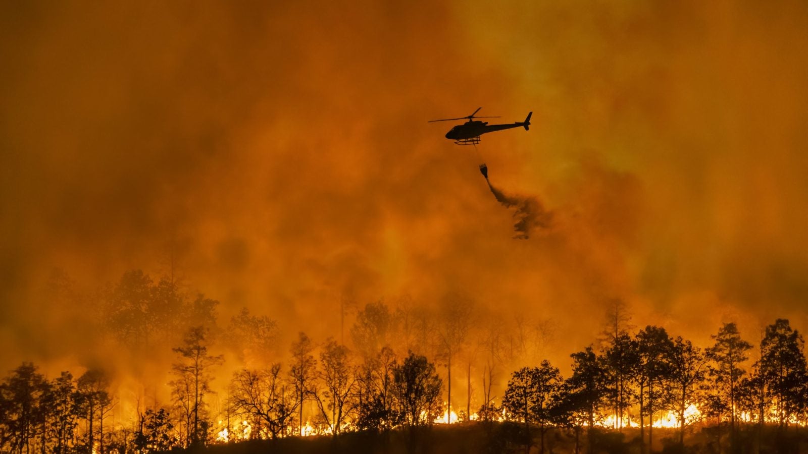 Helicopter pours water over a wildfire