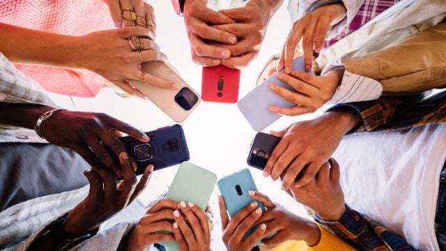 From the ground v iew of 7 people holding phones in their hands in a circle