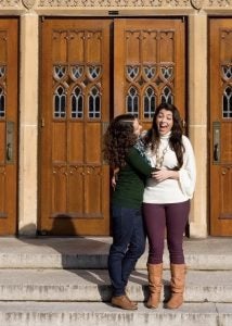 A woman hugs another woman as she laughs out loud.