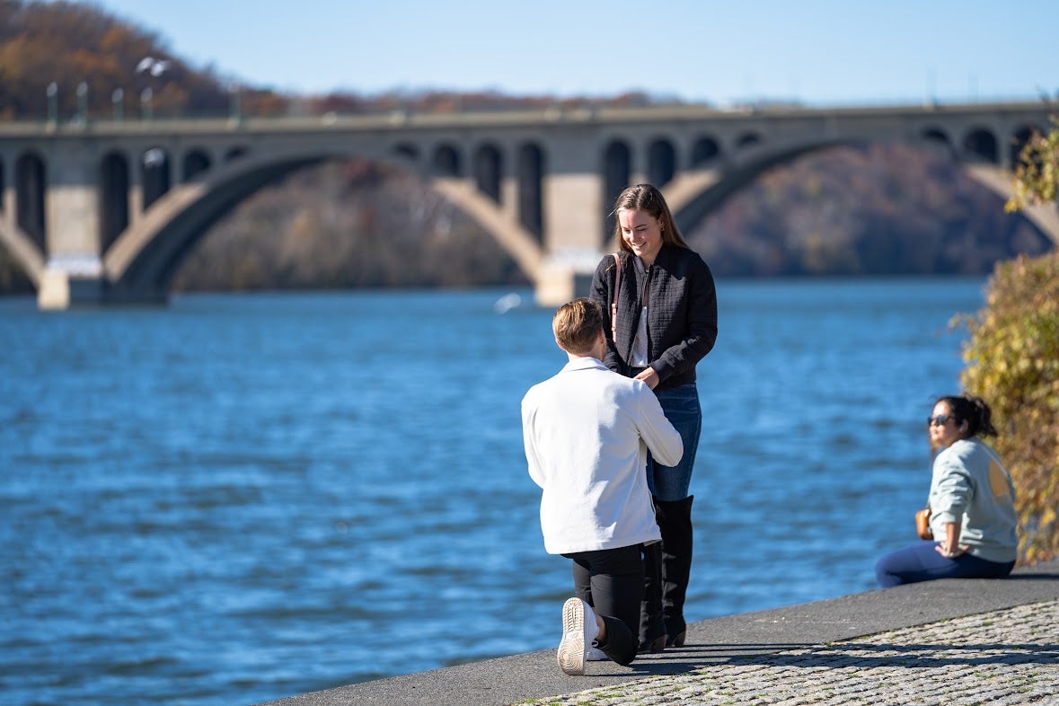 A man gets down on his knee and proposes next to the Potomac River.