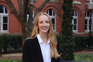 Young white woman in a black suit and white shirt outside