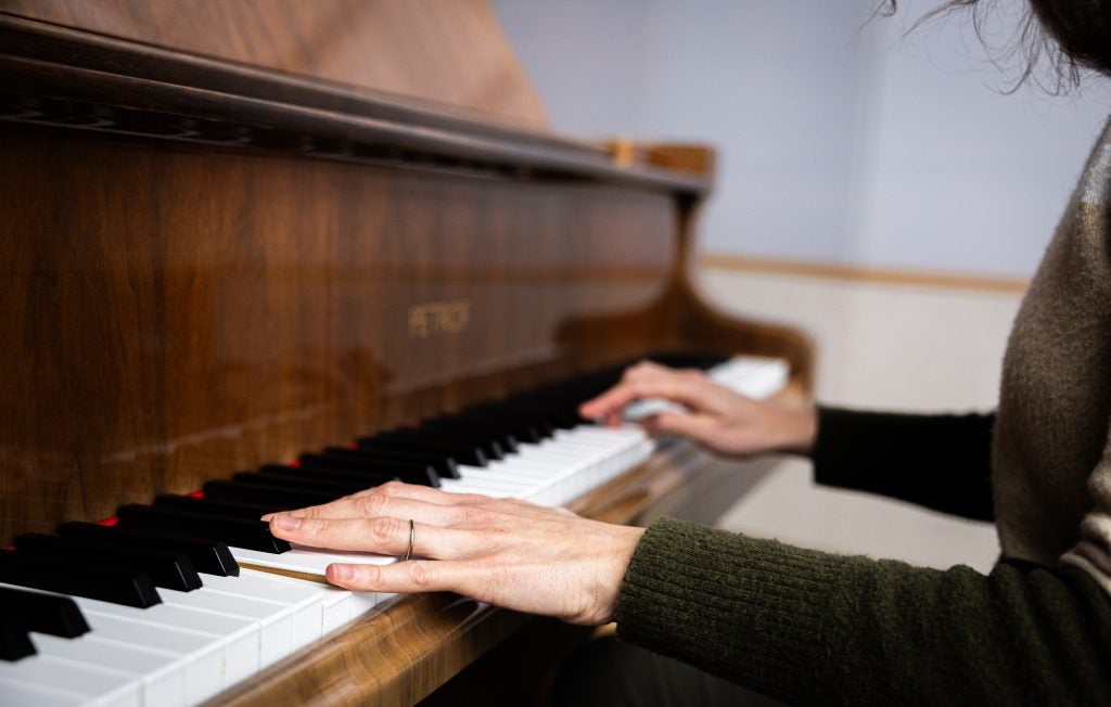 A person's hands play piano keys.