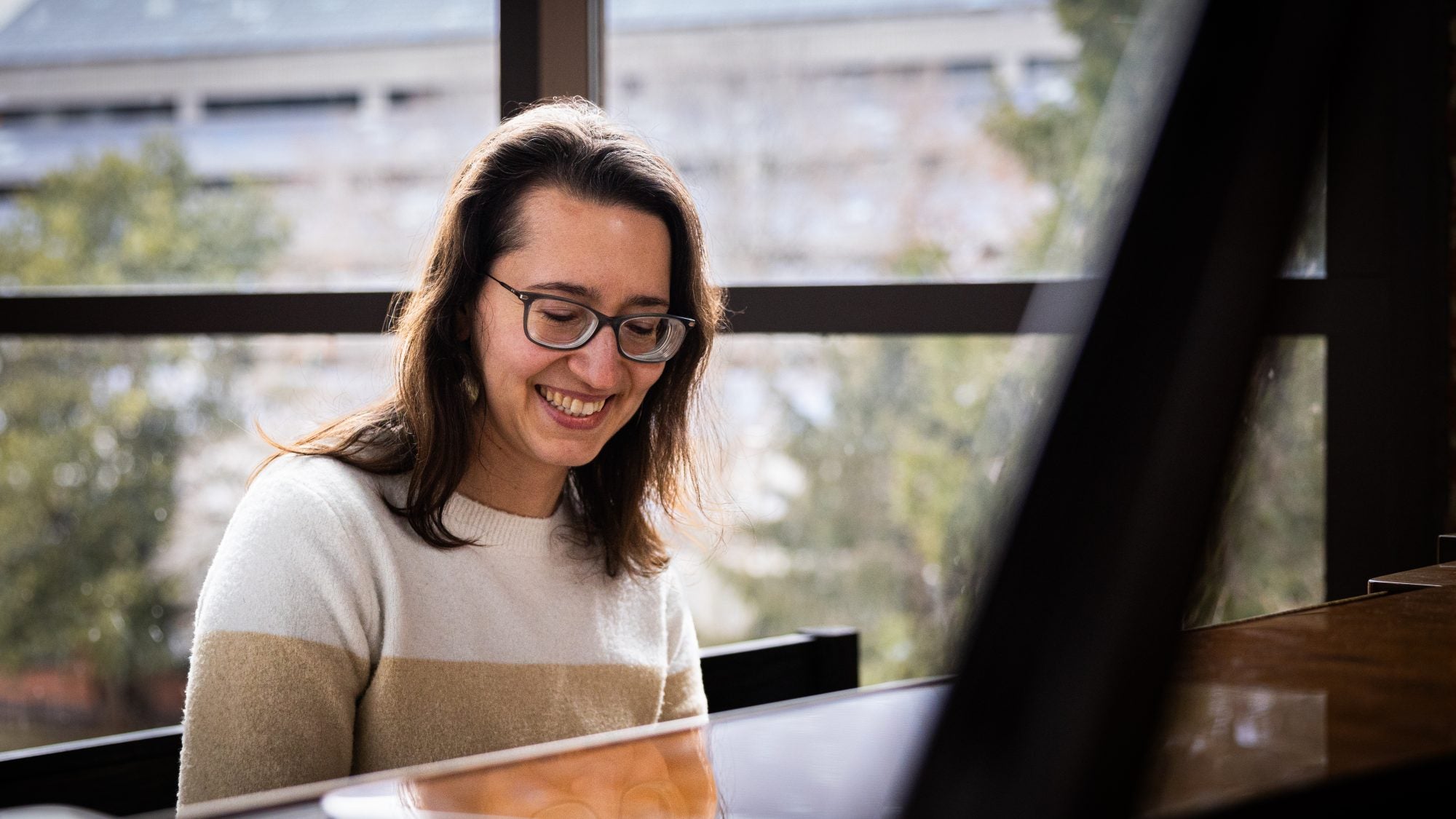 A woman smiles while playing the piano.