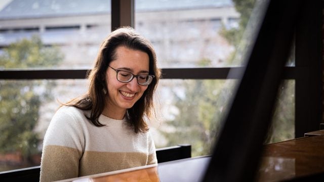 A woman smiles while playing the piano.