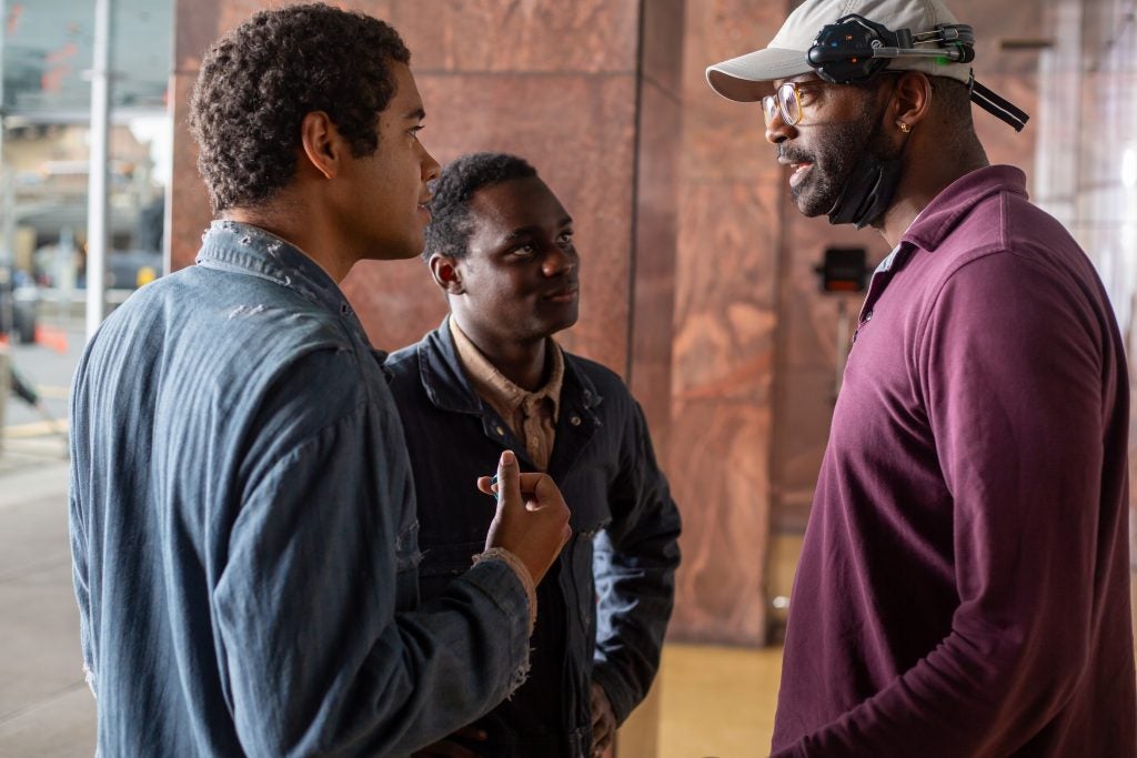 RaMell Ross with a headset talking to two Black actors on a set