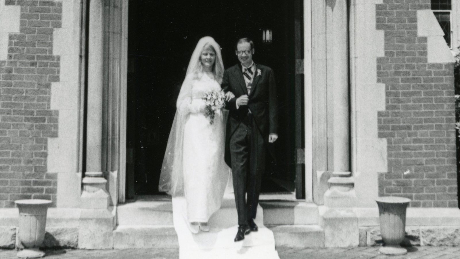 A black-and-white photo of a bride and groom leaving a chapel.