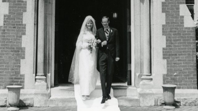 A black-and-white photo of a bride and groom leaving a chapel.