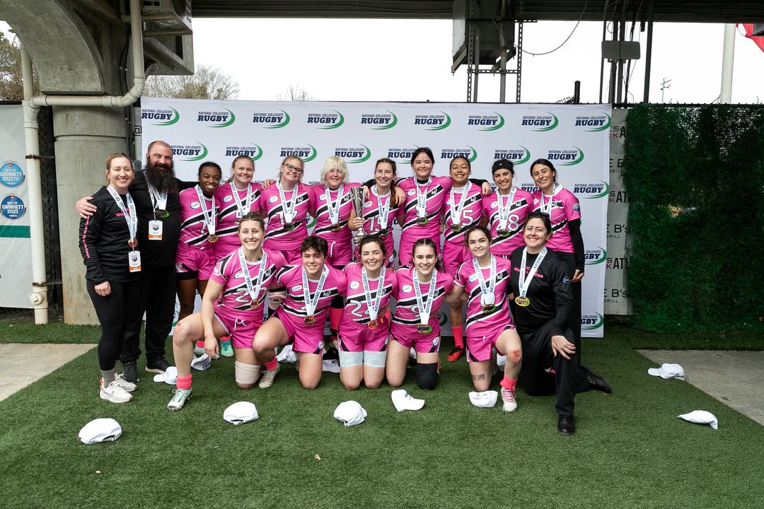 Team of young women rugby players wearing pink jerseys with medals around their necks