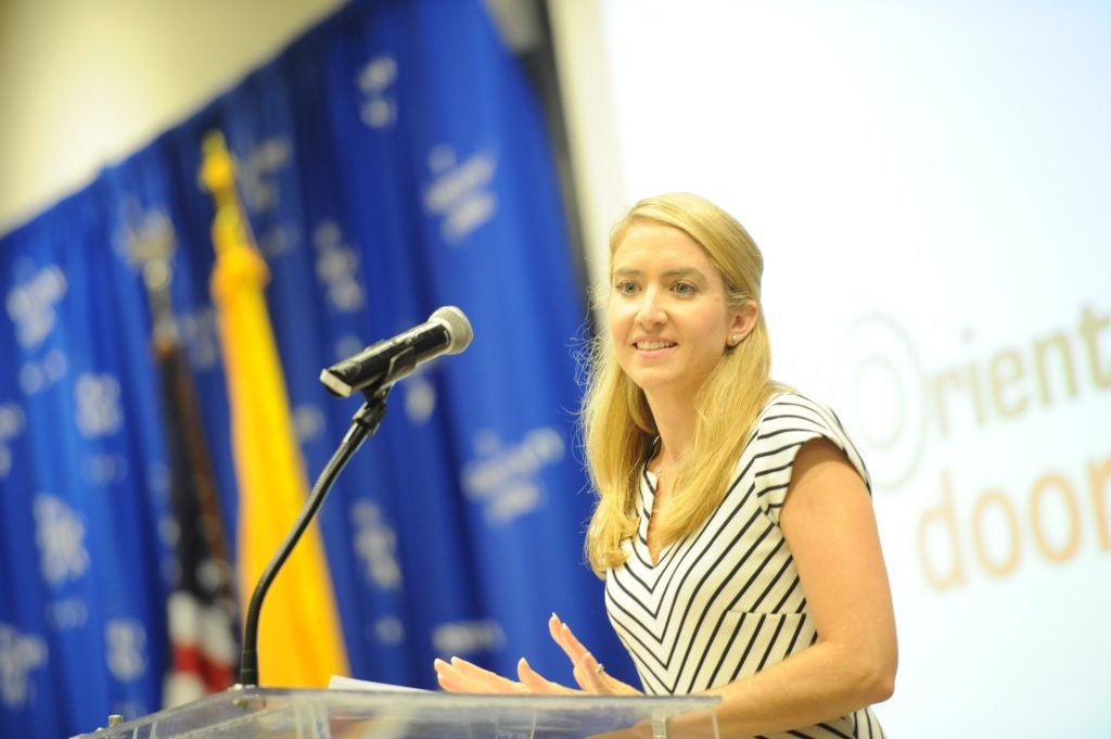 A blonde-haired woman speaks at a podium