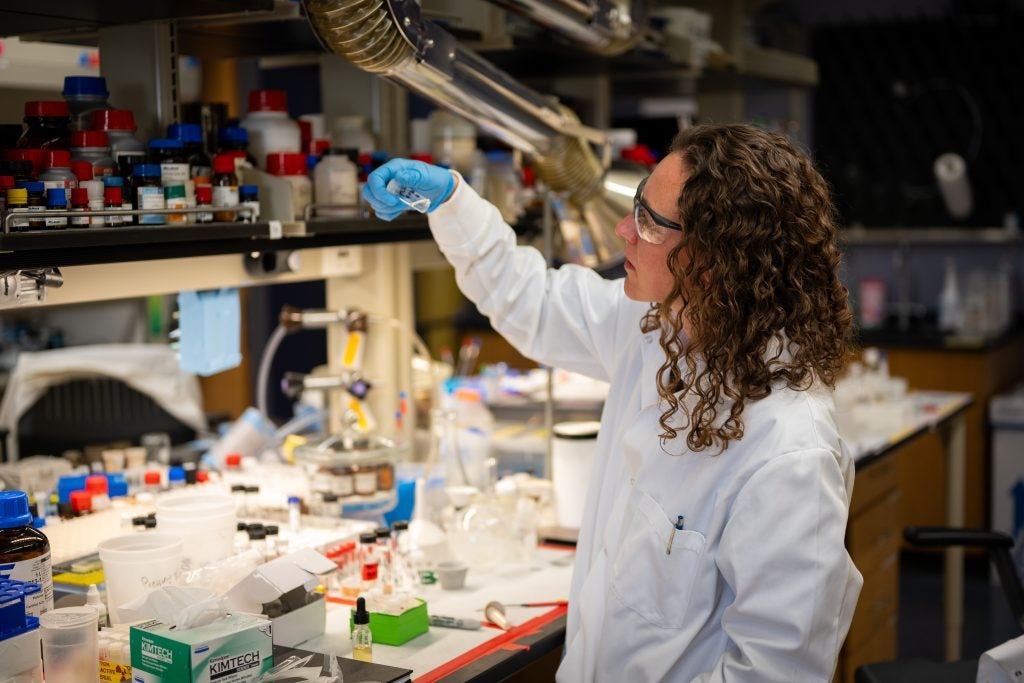 Knope examines a vial in a lab