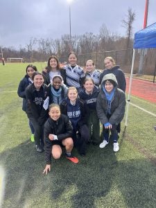 Team of women's rugby players pose for a photo on the field