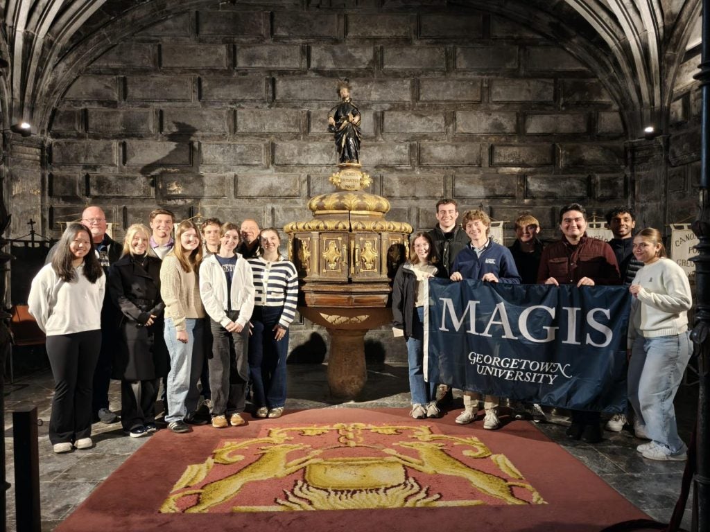 Students standing in a church while holding a Georgetown flag