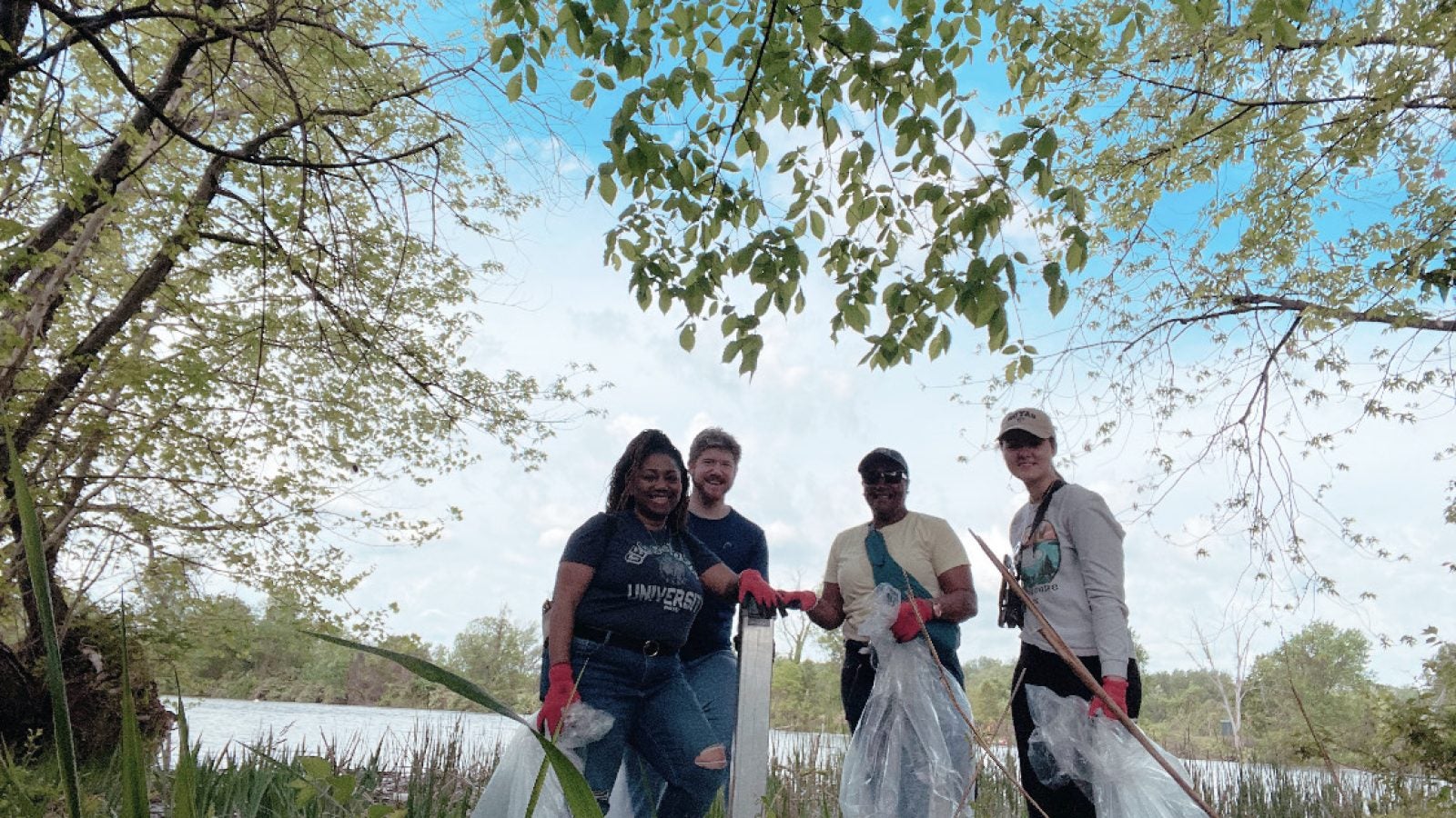 A group of students pick up trash along a river.