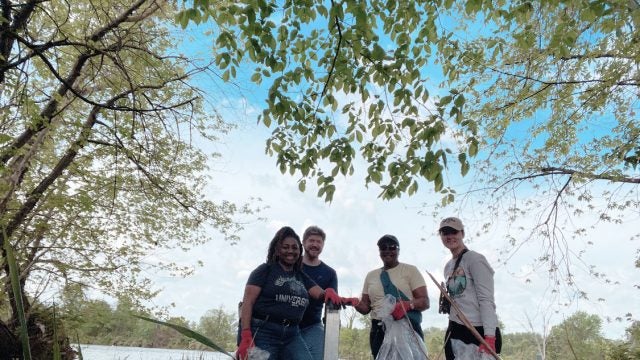 A group of students pick up trash along a river.