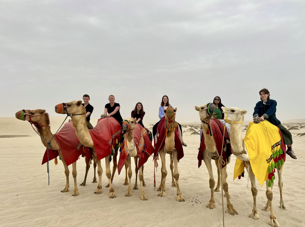 Six students on camels in a dessert