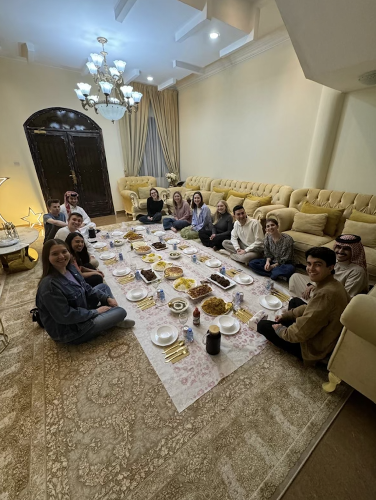 Students sitting down on the floor for a meal