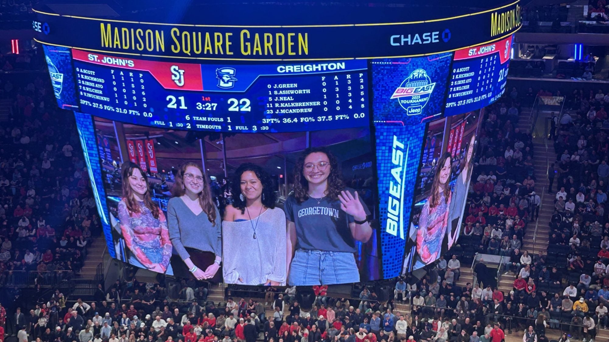 Four students appear on the jumbotron at Madison Square Arena