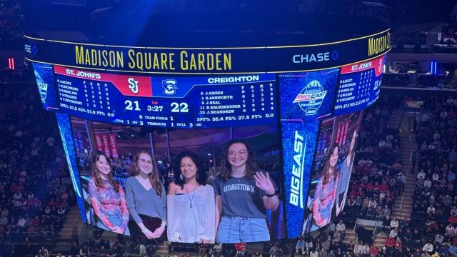 Four students appear on the jumbotron at Madison Square Arena