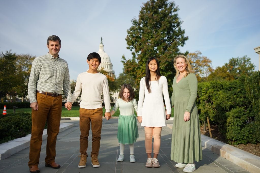 A family holds hands in front of the U.S. Capitol on a sunny day