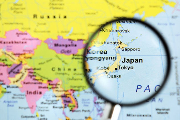 A closeup of a colorful map with a magnifying glass on Japan.