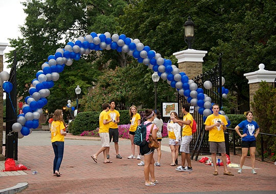 New Student Orientation volunteers and leaders wait for students to enter campus under the iconic balloon arch. 