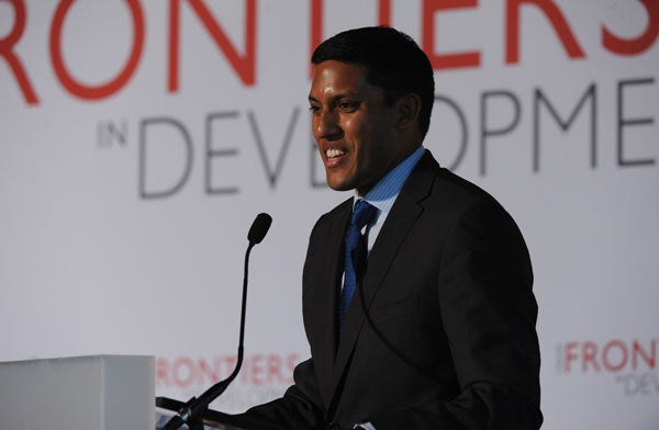 Rajiv Shah speaks into a microphone in front of a backdrop