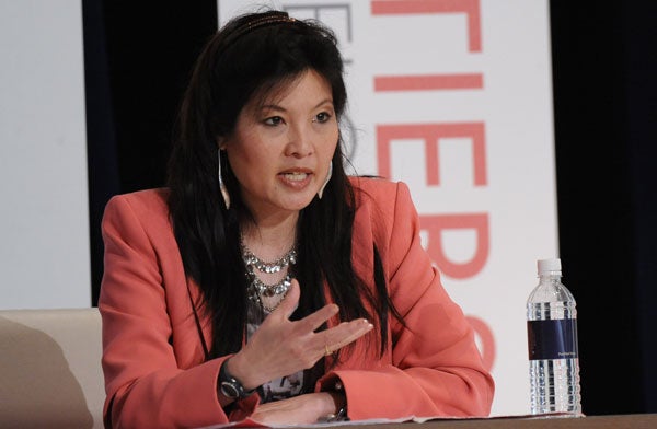 Sheryl WuDunn speaks in front of a backdrop