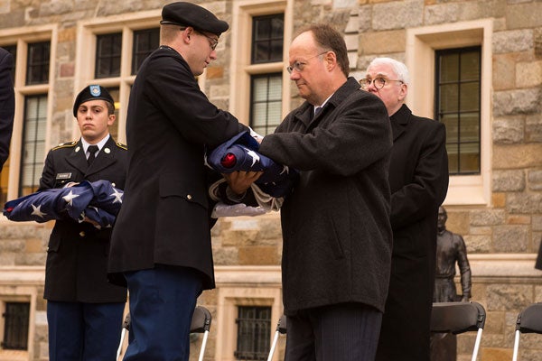 Georgetown President John J. DeGioia receives the American flag from a member of the Hoya Battalion.