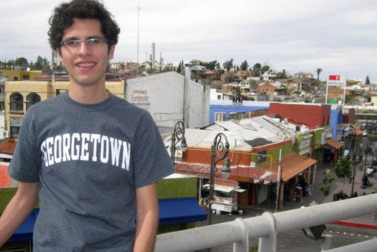 Zenen Jaimes stands on a roof overlooking a small city