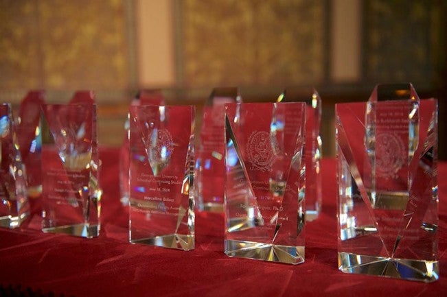 Clear glass awards sit atop a red velvet cloth on a table.