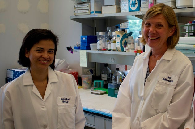 Sonia de Assis and Leena Hilakivi-Clarke smile in lab coats in their lab